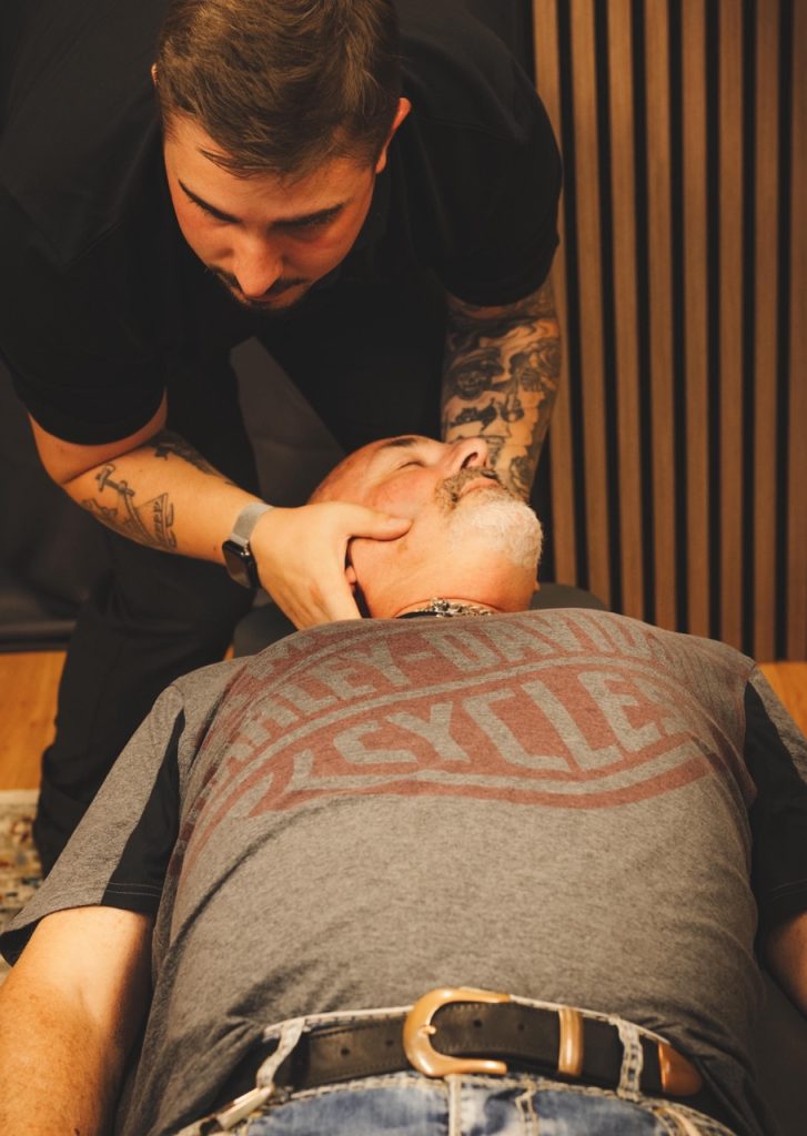 Robin behandlar nacke och huvud på patient på behandlingsbänk.