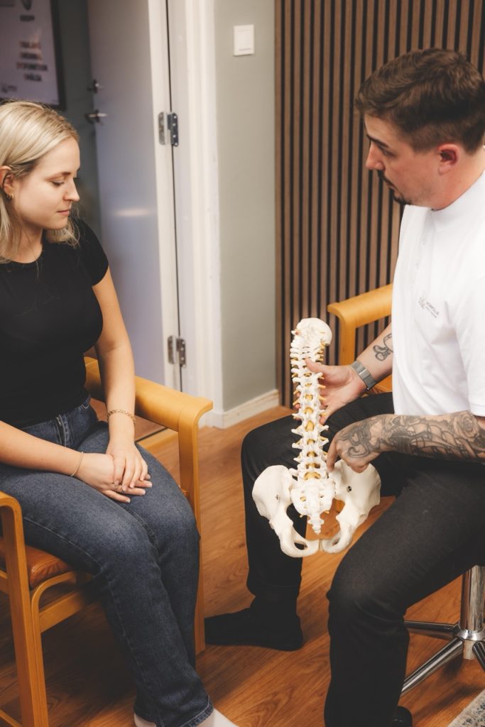 Robin använder anatomisk modell för att förklara besvär och funktion.