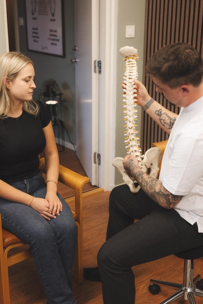 Robin visar ryggradsmodell för patient under konsultation i Norrtälje.